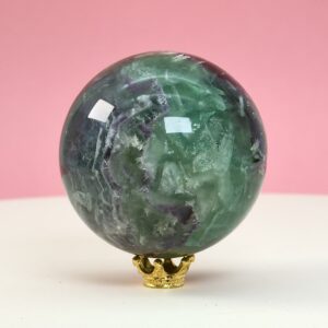 Fluorit regnbue krystal sten kugle på hvid plade med lyserød baggrund