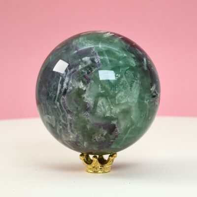 Fluorit regnbue krystal sten kugle på hvid plade med lyserød baggrund