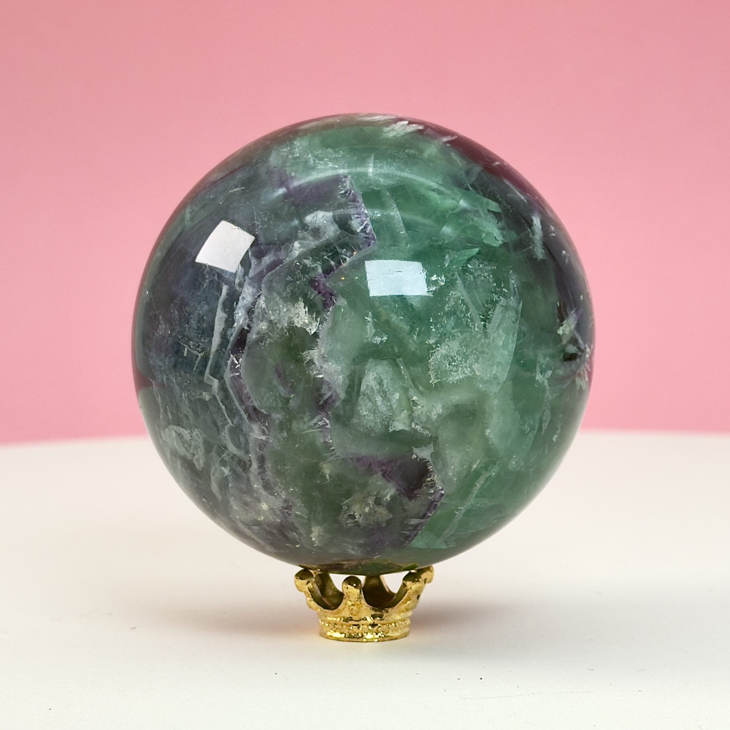 Fluorit regnbue krystal sten kugle på hvid plade med lyserød baggrund