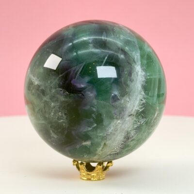 Fluorit regnbue krystal sten kugle på hvid plade med lyserød baggrund