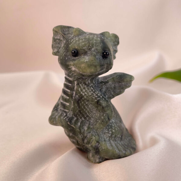 Serpentin krystal babydrage på hvid baggrund med grønt blad