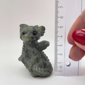 Serpentin krystal babydrage ved siden af lineal på hvid baggrund