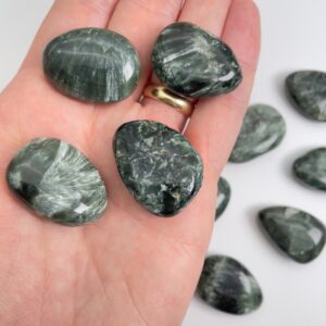 Serafinit håndpoleret krystal lommesten på hånd med hvid baggrund