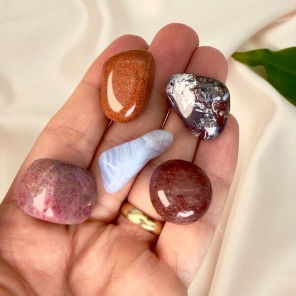 Indre ro krystal healingssæt liggende på hånd med hvid baggrund med grønt blad