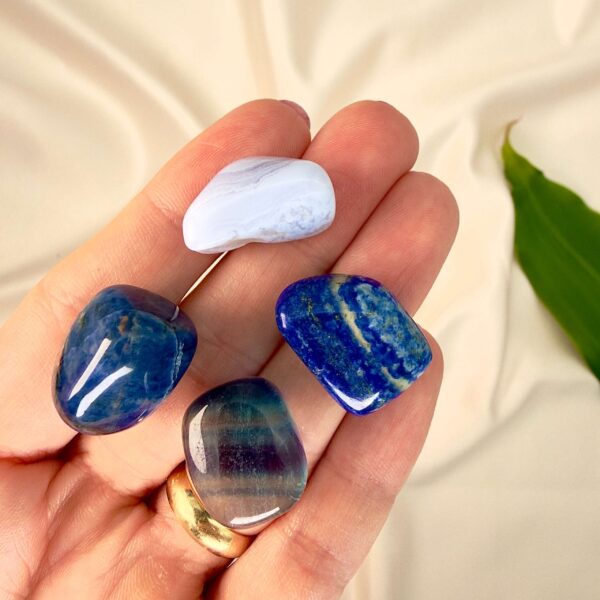 Kommunikation krystal healingssæt liggende på hånd med hvid baggrund med grønt blad