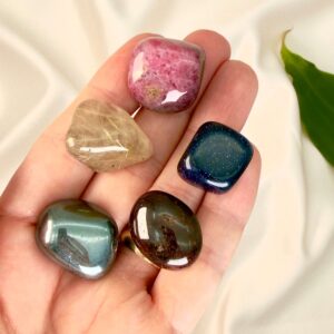 Parforhold krystal healingssæt liggende på hånd med hvid baggrund med grønt blad