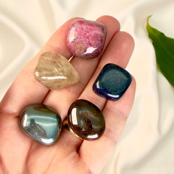 Parforhold krystal healingssæt liggende på hånd med hvid baggrund med grønt blad