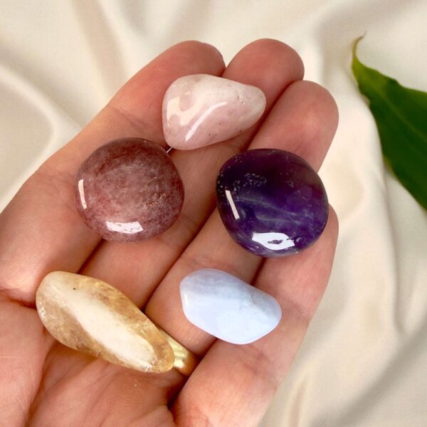 Selvværd selvtillid krystal healingssæt liggende på hånd med hvid baggrund med grønt blad