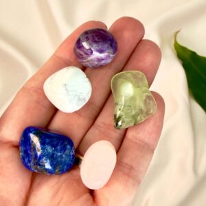 Søvnløshed krystal healingssæt liggende på hånd med hvid baggrund med grønt blad