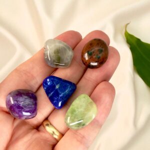 Spirituel udvikling krystal healingssæt liggende på hånd med hvid baggrund med grønt blad