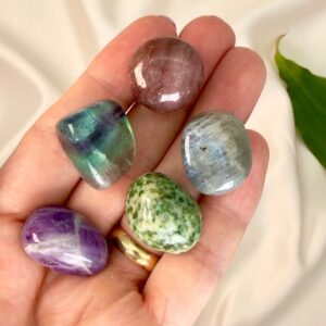 Stress krystal healingssæt liggende på hånd med hvid baggrund med grønt blad