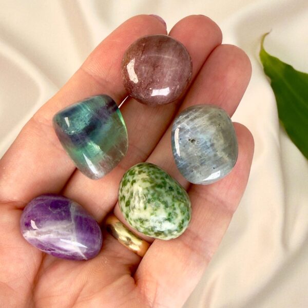 Stress krystal healingssæt liggende på hånd med hvid baggrund med grønt blad