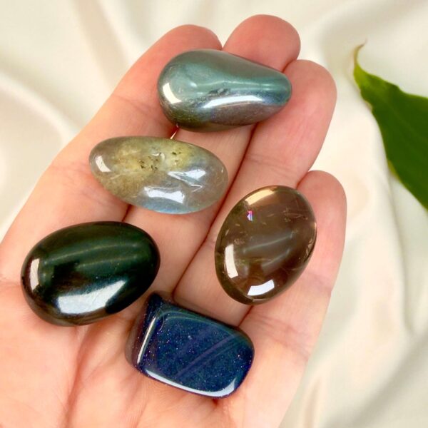 Tankemylder krystal healingssæt liggende på hånd med hvid baggrund med grønt blad