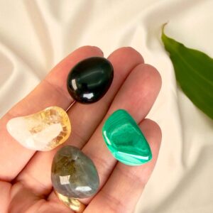 Transformation krystal healingssæt liggende på hånd med hvid baggrund med grønt blad