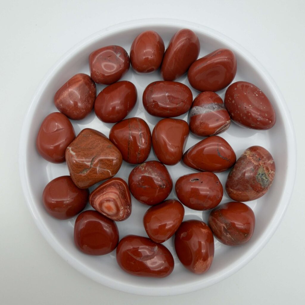 rød jaspis krystaller i hvidt fad på hvid baggrund