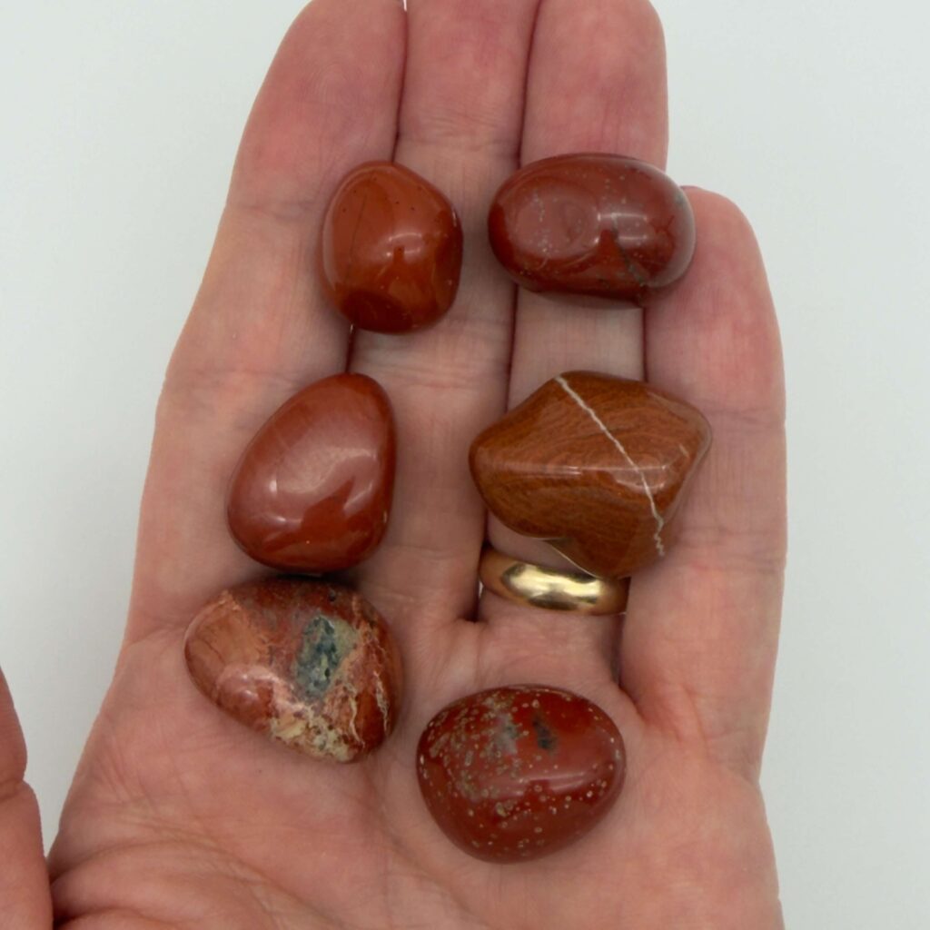 rød jaspis krystaller i hånd med hvid baggrund