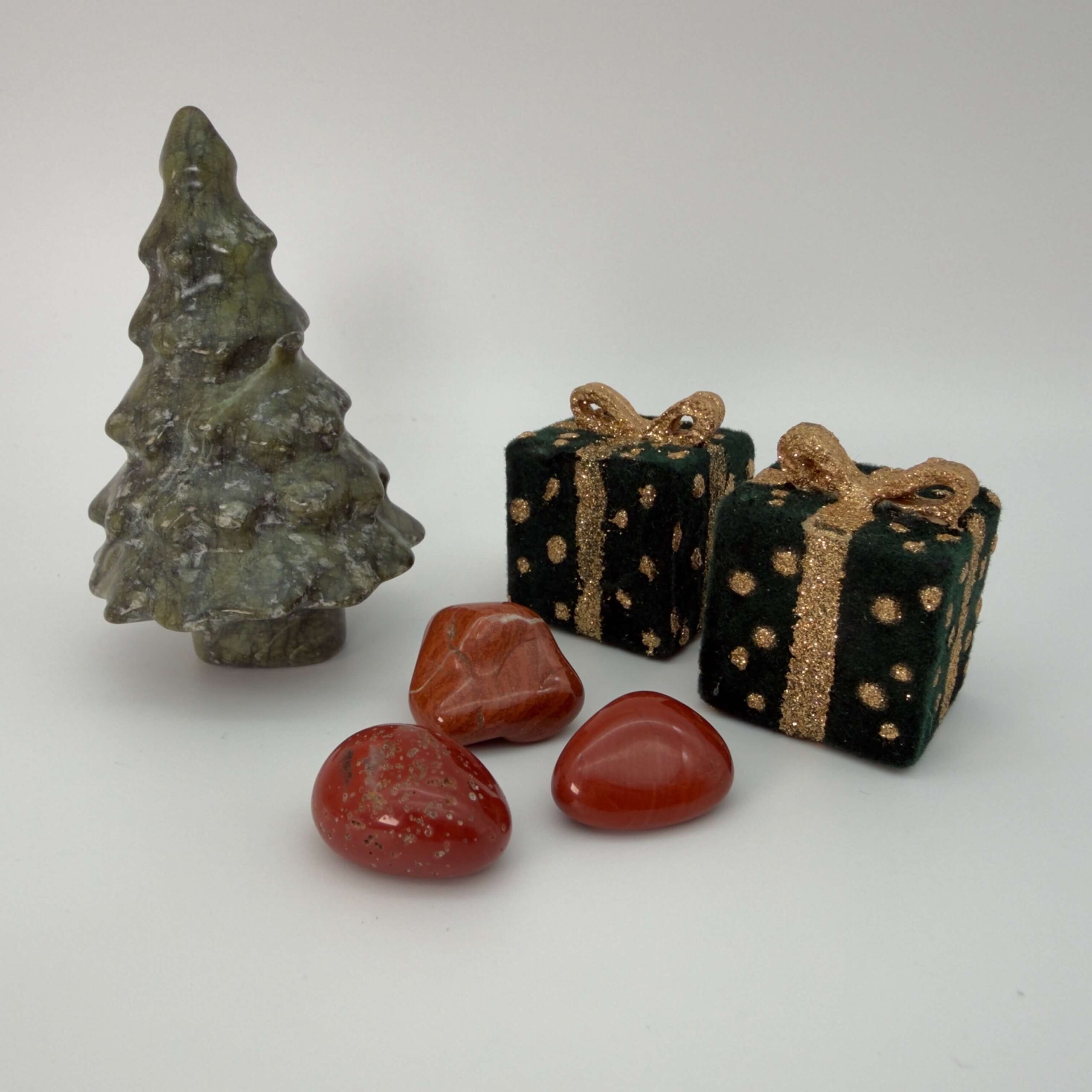 rød jaspis krystaller ved siden af juletræ og pakker på hvid baggrund