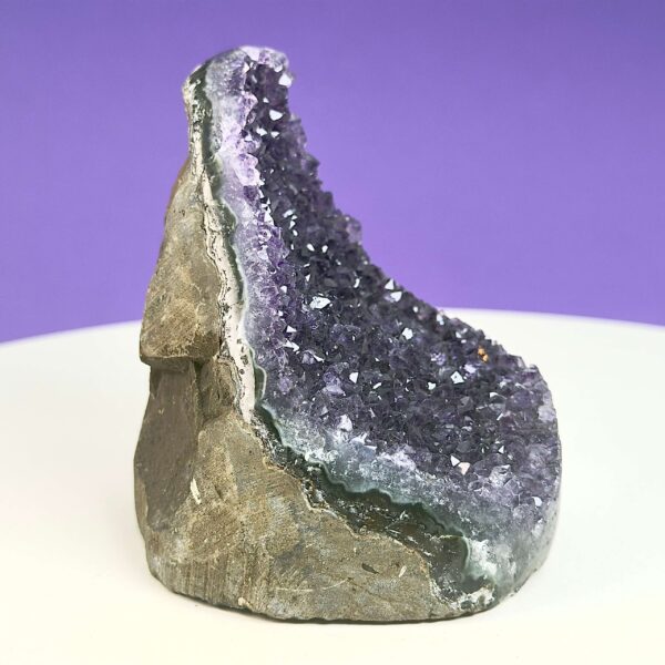 Ametyst krystal rå grotte klynge sten på hvid plade med lilla baggrund fra siden