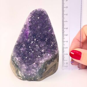 Ametyst krystal rå grotte klynge sten ved siden af lineal på hvid baggrund