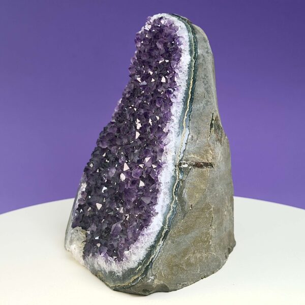 Ametyst krystal rå grotte klynge sten på hvid plade med lilla baggrund fra siden