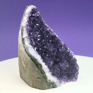 Ametyst krystal rå grotte klynge sten på hvid plade med lilla baggrund fra siden