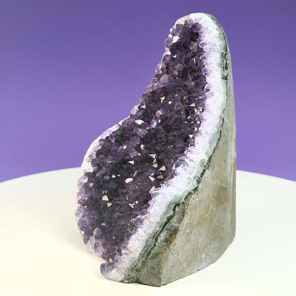 Ametyst krystal rå grotte klynge sten på hvid plade med lilla baggrund fra siden