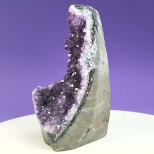 Ametyst krystal rå grotte klynge sten på hvid plade med lilla baggrund fra siden