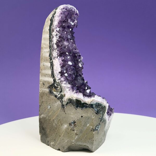 Ametyst krystal rå grotte klynge sten på hvid plade med lilla baggrund fra siden