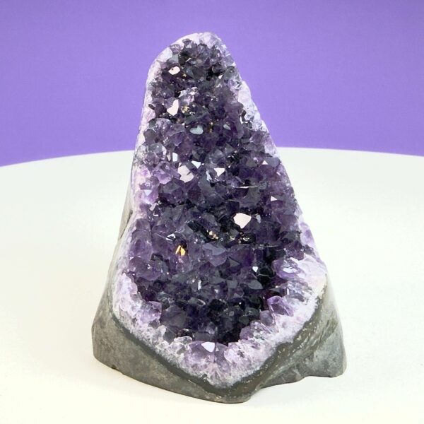 Ametyst krystal rå grotte klynge sten på hvid plade med lilla baggrund