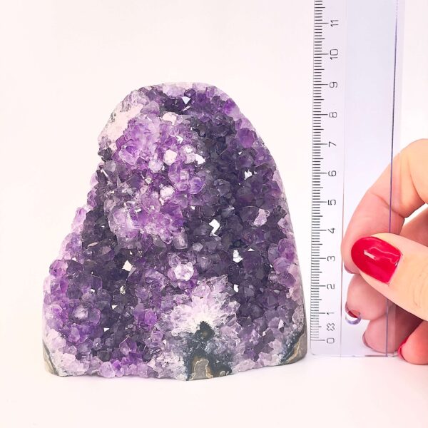 Ametyst krystal rå grotte klynge sten ved siden af lineal på hvid baggrund