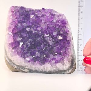 Ametyst krystal rå grotte klynge sten ved siden af lineal på hvid baggrund