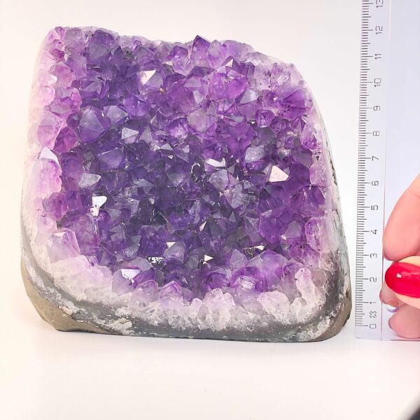 Ametyst krystal rå grotte klynge sten ved siden af lineal på hvid baggrund