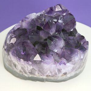 Ametyst krystal rå grotte klynge sten på hvid plade med lilla baggrund