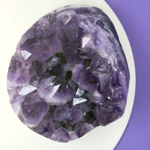 Ametyst krystal rå grotte klynge sten på hvid plade med lilla baggrund