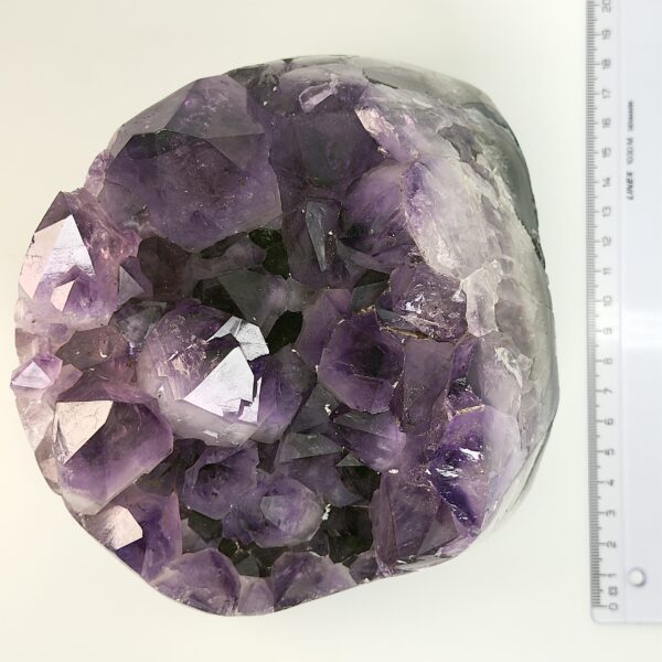 Ametyst krystal rå grotte klynge sten ved siden af lineal på hvid baggrund