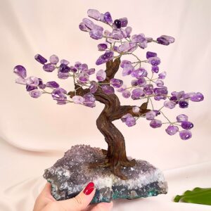 Ametyst træ på krystal bund i hånd med lys baggrund og grønt blad