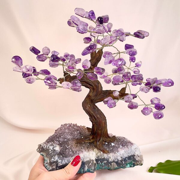 Ametyst træ på krystal bund i hånd med lys baggrund og grønt blad