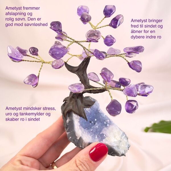 Ametyst træ på krystal bund i hånd med lys baggrund og grønt blad