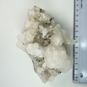 Bjergkrystal krystal klynge brud ved siden af lineal på hvid baggrund