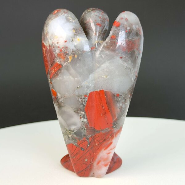 Blodsten krystal engel bagfra på hvid plade med sort baggrund