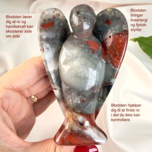 Blodsten krystal engel mellem fingre med hvid baggrund og grønt blad med tags