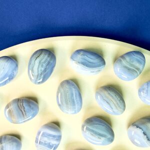 Blondeagat håndpoleret krystal lommesten på træfad med blå baggrund