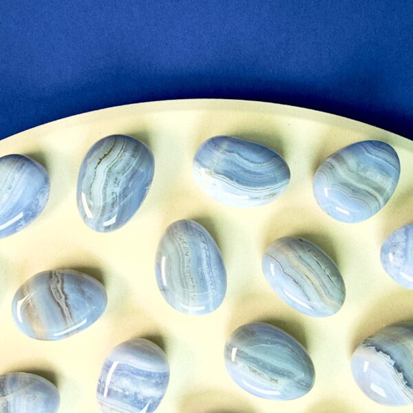 Blondeagat håndpoleret krystal lommesten på træfad med blå baggrund