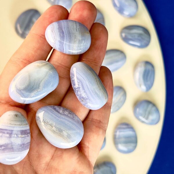 Blondeagat håndpoleret krystal lommesten i hånd med hvid og blå baggrund