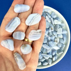 Blondeagat krystal lommesten på hånd med hvidt fad med blondeagater på blå baggrund