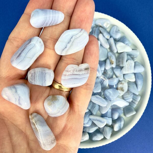 Blondeagat krystal lommesten på hånd med hvidt fad med blondeagater på blå baggrund