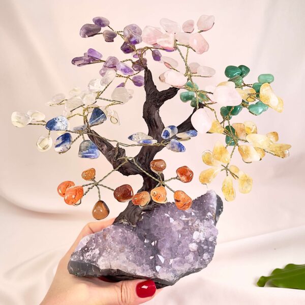 Ametyst bjergkrystal citrin karneol aventurin sodalit rosakvarts træ på krystal bund i hånd med lys baggrund og grønt blad