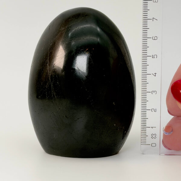 Sort Agat Freeform krystal sten i hånd med lineal på hvid baggrund