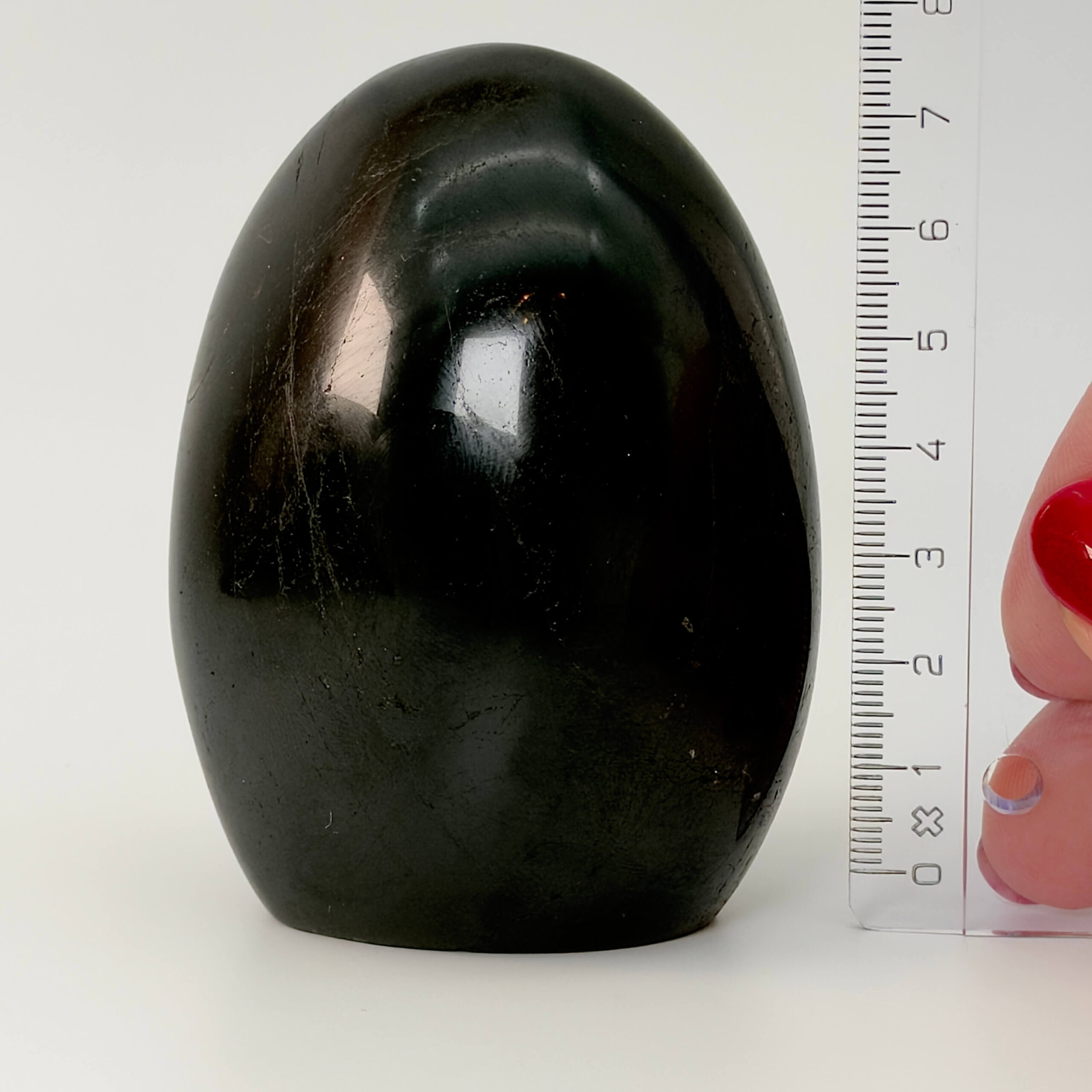 Sort Agat Freeform krystal sten i hånd med lineal på hvid baggrund