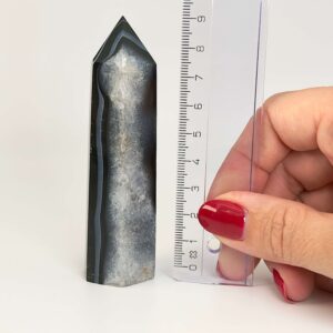 Agat sort krystal tårn sten på hvid baggrund med lineal i hånd